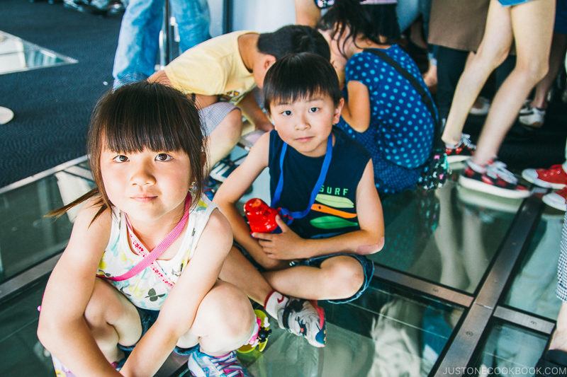 girl and boy sitting on top of glass floor