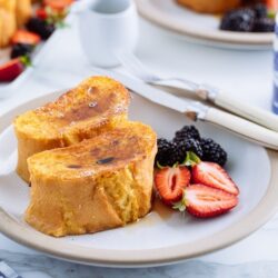 A plate containing French toast, strawberries, and blackberries.