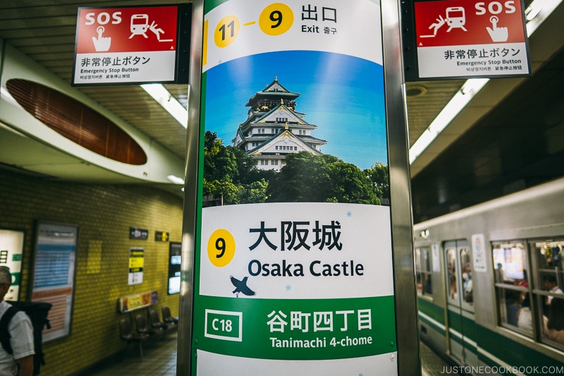 A sign for Osaka Castle on the side of a train station