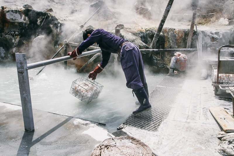 staff dropping uncooked eggs into boiling hot spring - Hakone Ropeway and Owakudani Hell Valley | www.justonecookbook.com