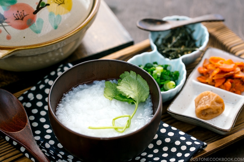Japanese rice porridge served in a bowl with salmon, green onion, pickled plums, and shredded seaweed.