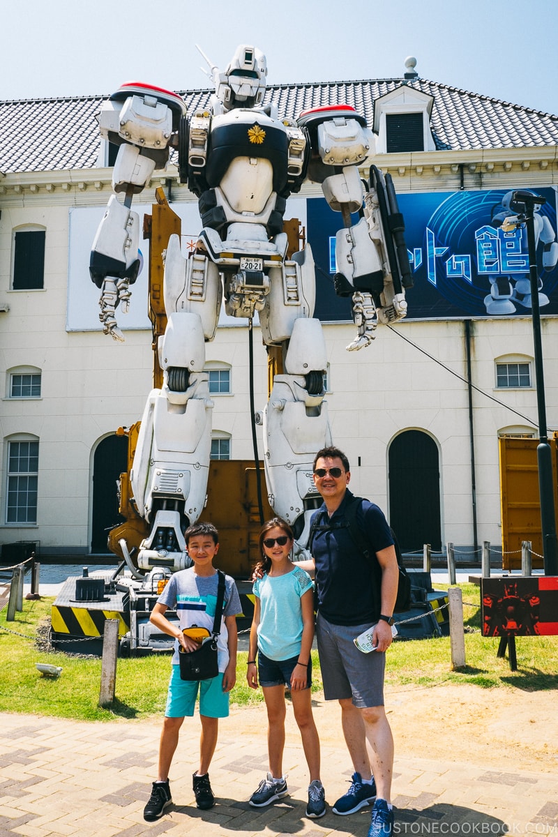 a man and two children standing in front of a robot