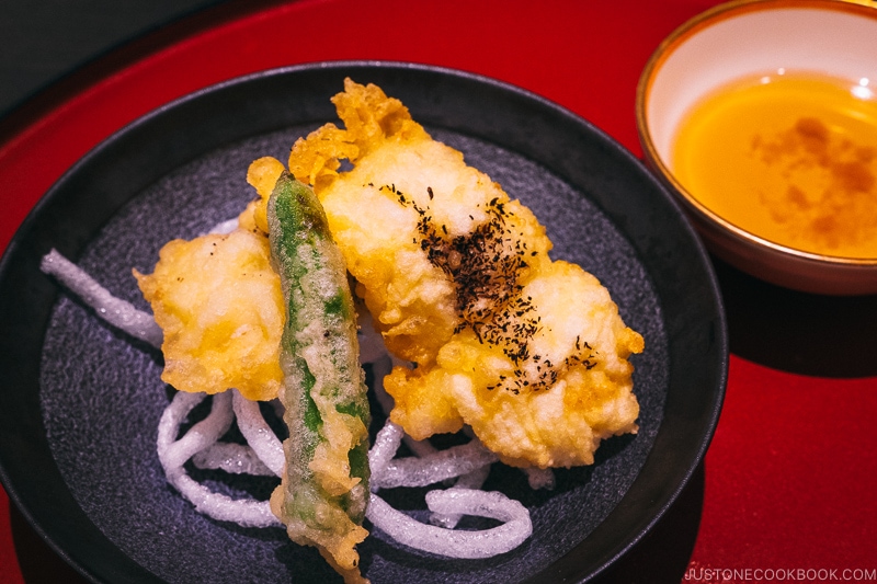 deep fried hamo fish on a black plate