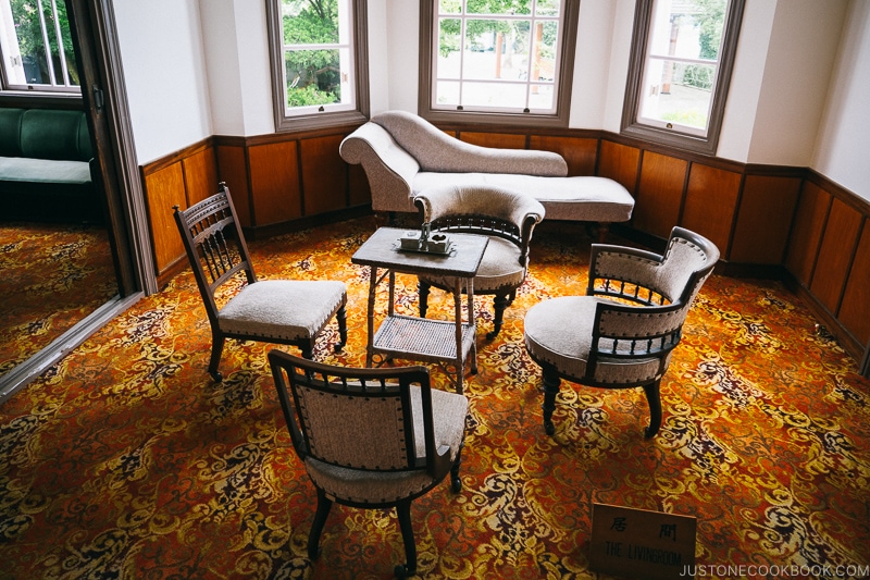 a carpeted room with a lounger and small table with four chairs around it