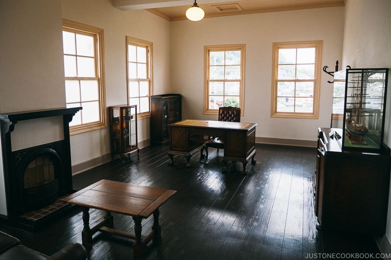 room with a fireplace, antique coffee table, office desk and chair with dark wooden floor