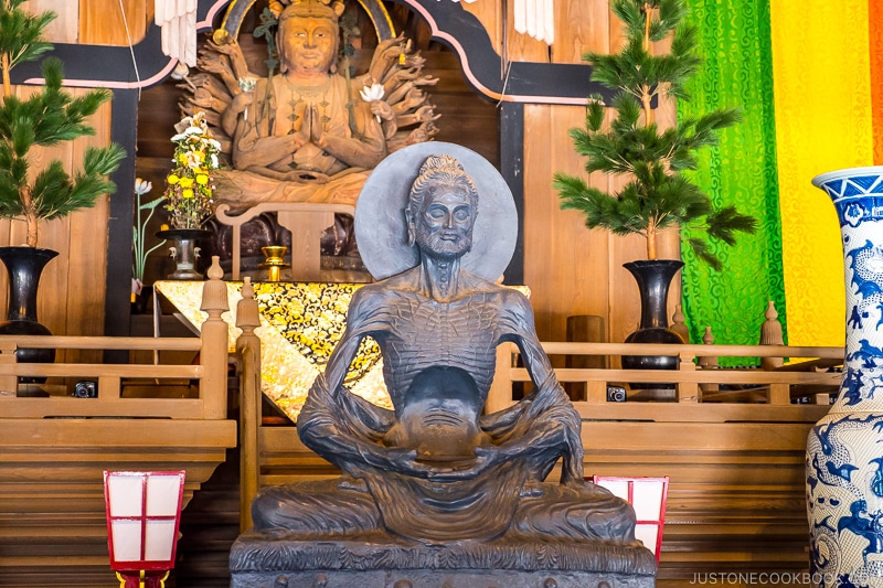 a dark statue of a boney deity meditating