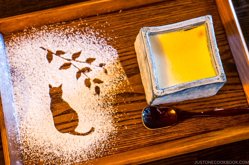 a wooden tray with powdered sugar on the left and Japanese purin on the right