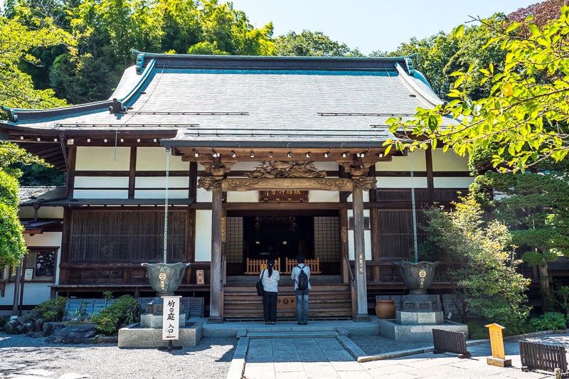 two people praying in front of a one story temple