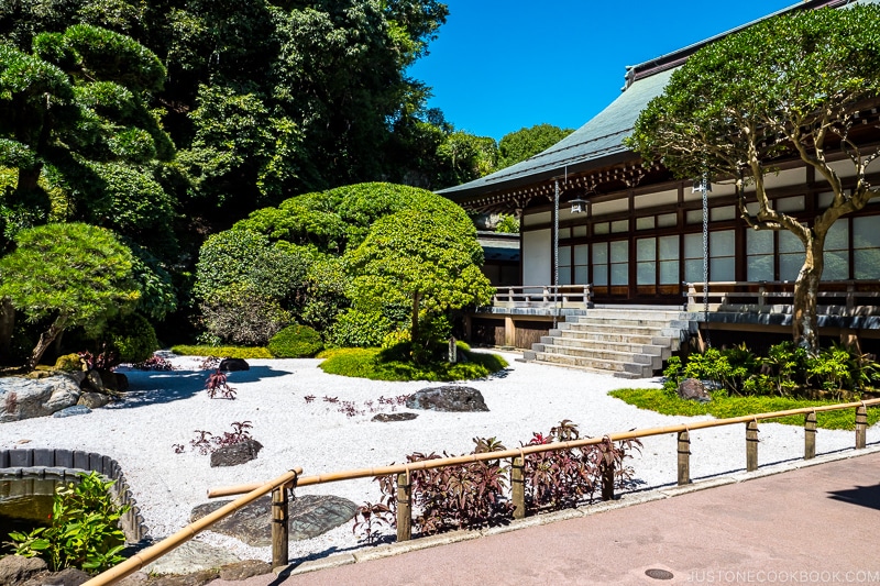 a rock garden next to a temple with trees in the back