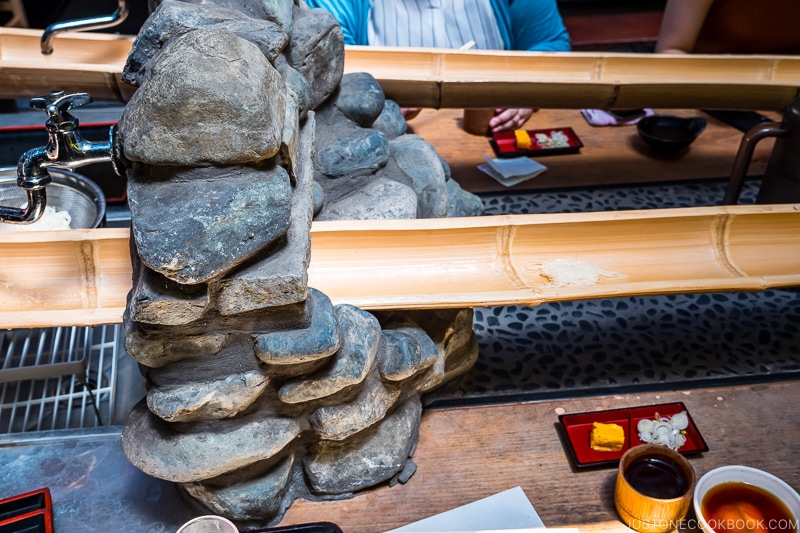 somen flowing down a bamboo chute on top of a table