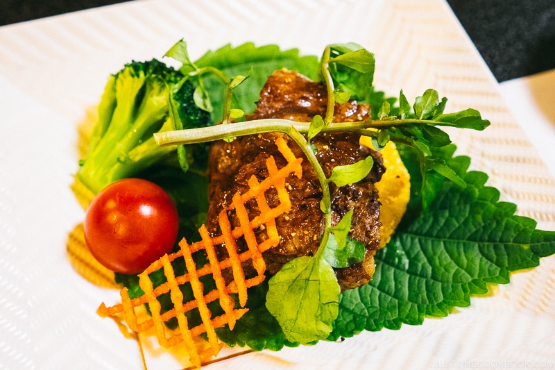 steak and broccoli on top of shiso leaf