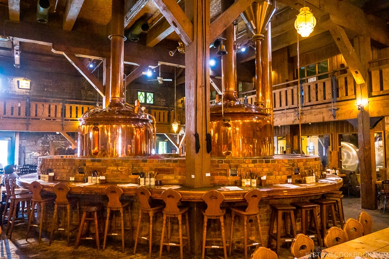 stools surrounding two golden beer vats surrounded by bricks