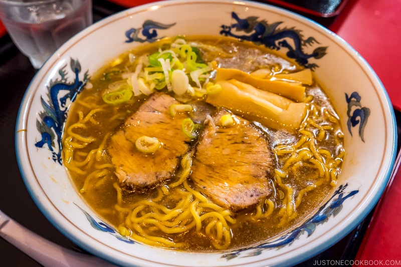 chashu ramen with bamboo in a white bowl on top of a black tray