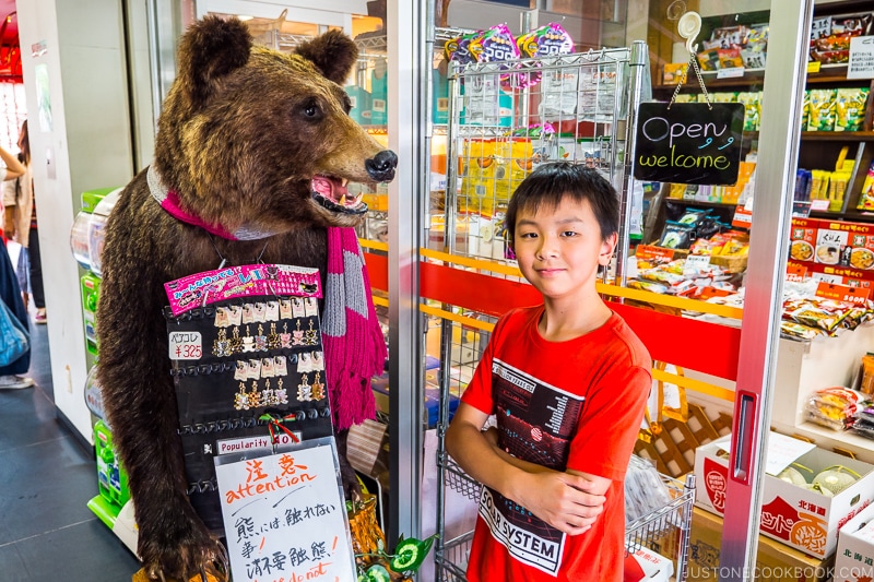boy standing next to a bear next to a gift shop