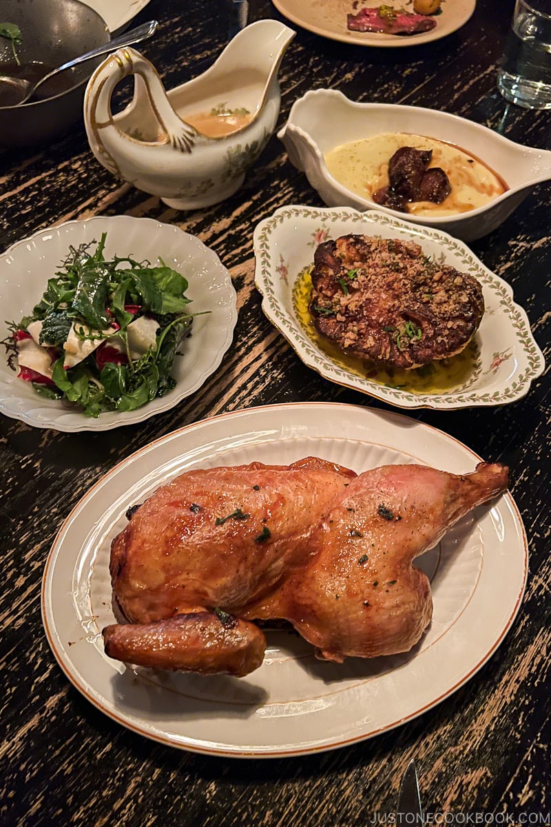 half roasted chicken with sides and gravy on a wood table