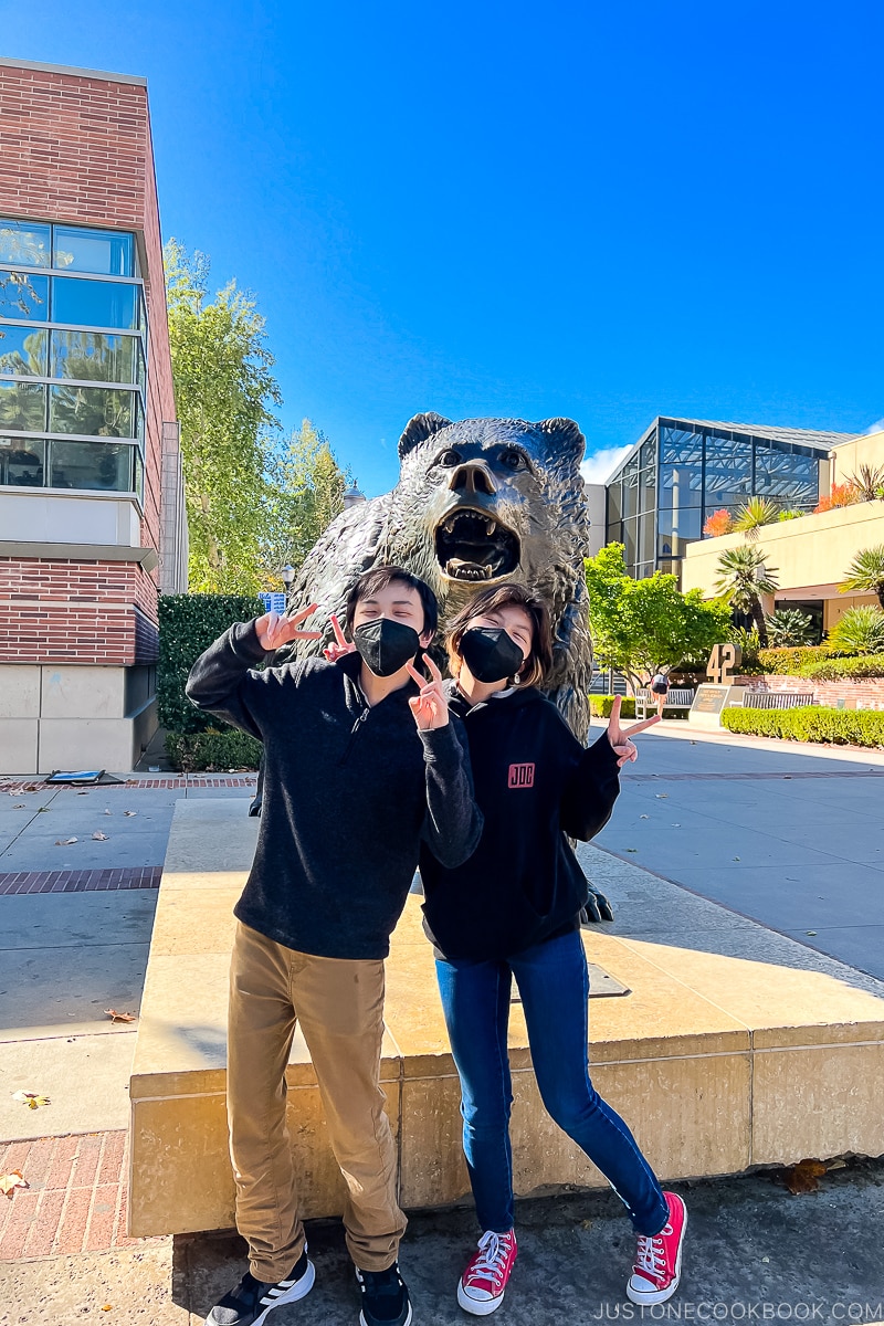 a boy and a girl pose in front of Bruin Statue