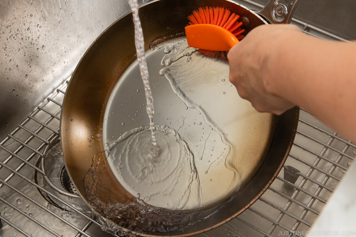 washing fry pan in a sink
