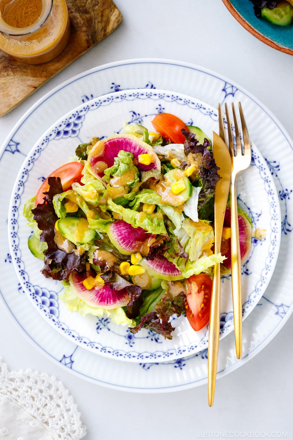 A plate of green salad along with a glass jar of homemade miso dressing.