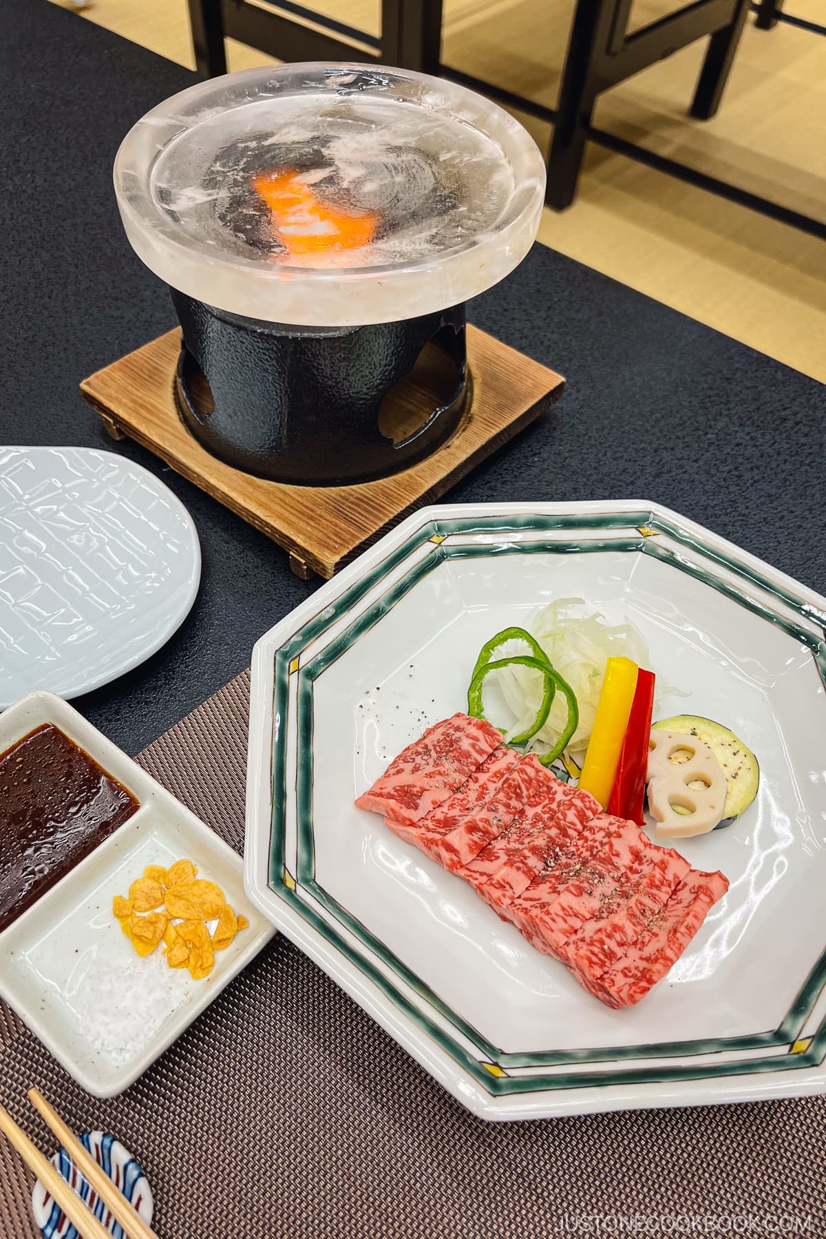 beef on a white plate next to a small grill