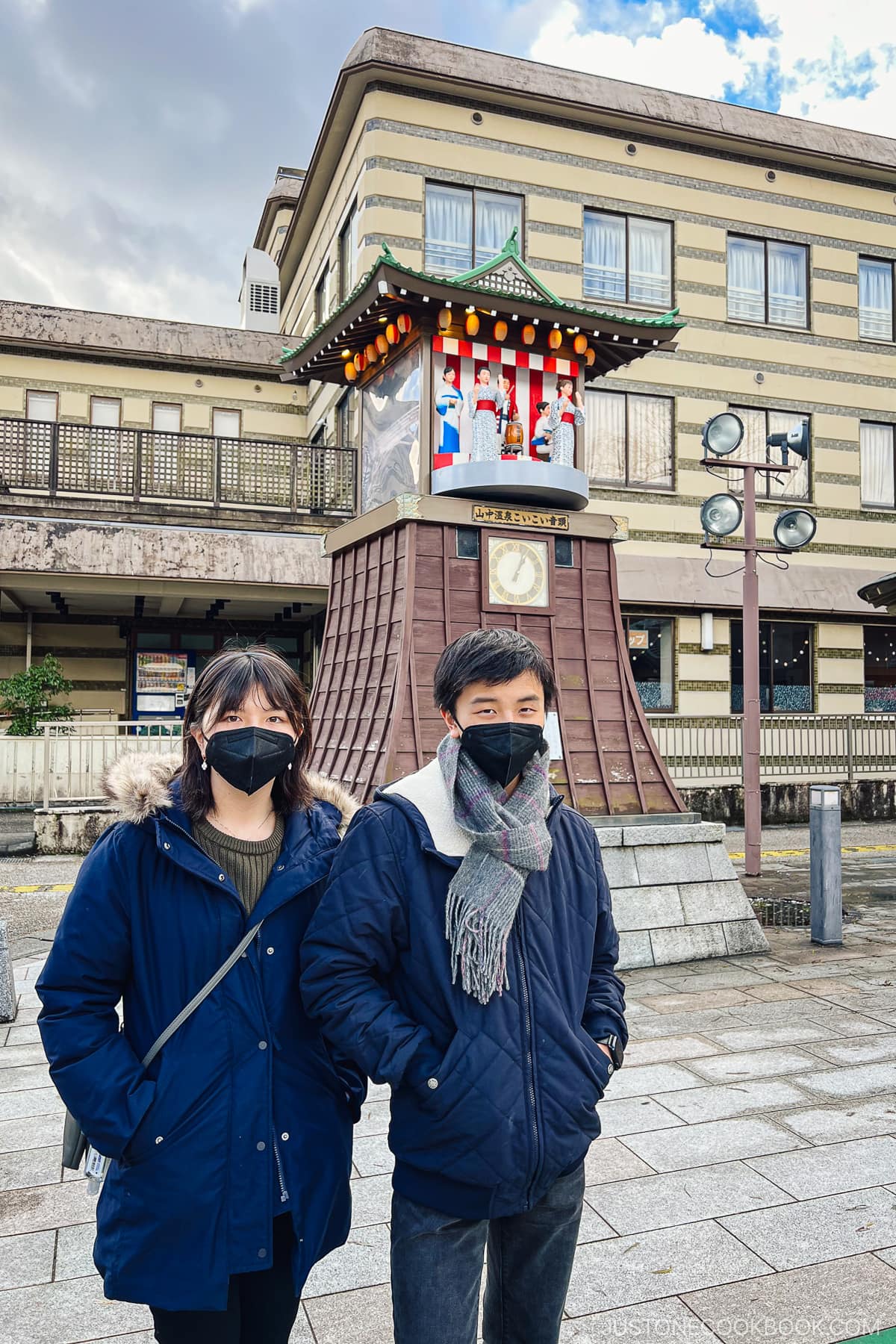 two teenagers in front of a clock bell tower