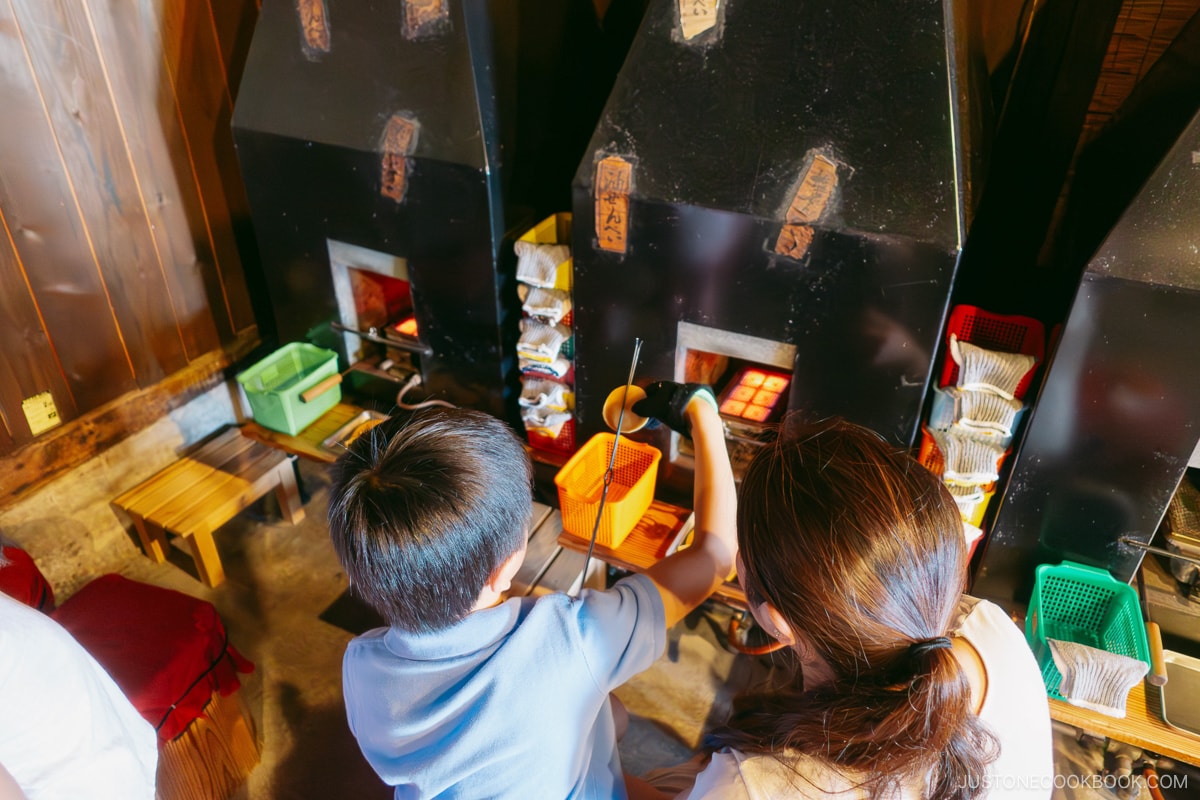 children making their own rice crackers in front of the oven