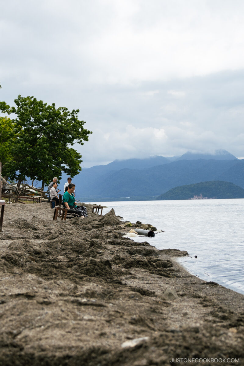 People sitting at Sunayu Onsen next to Lake Kussharo