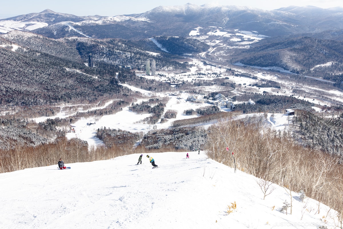 Skiers and snowboarders on the ski slopes with Tomamu Ski resort in the background