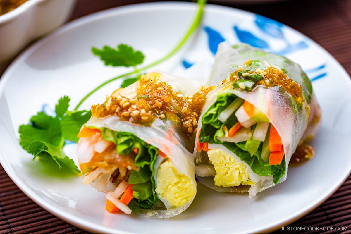 A white plate containing Pork Spring Rolls with Ponzu.