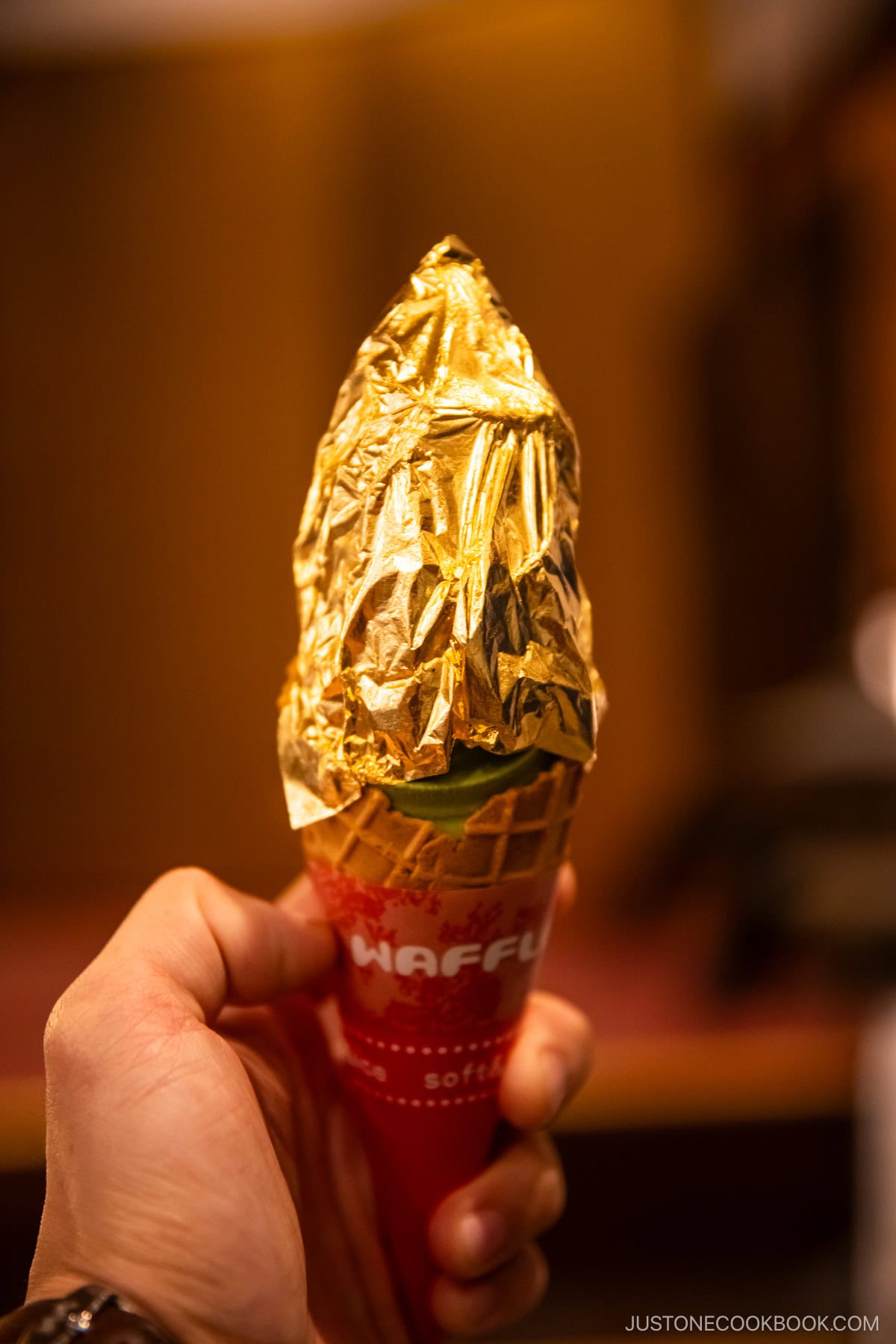 Matcha soft serve in a waffle cone topped with gold leaf