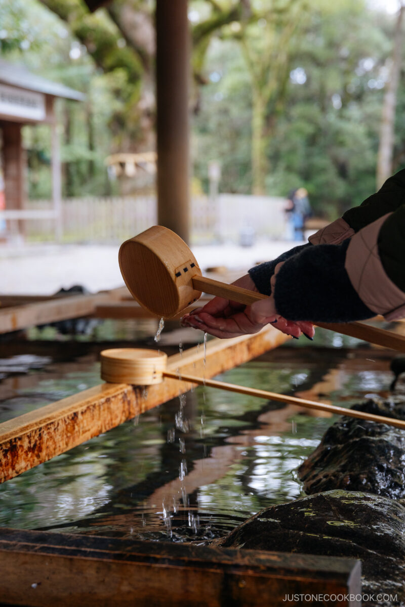 a person rinsing their hand with wood ladle
