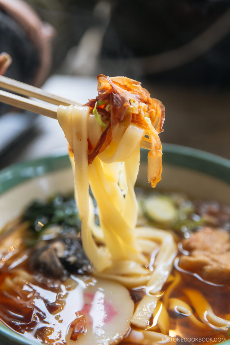 a pair of chopsticks holding udon noodles