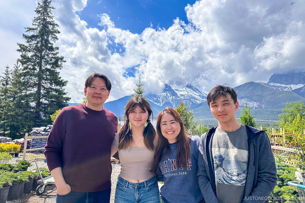 four people standing in front of scenic mountain peaks
