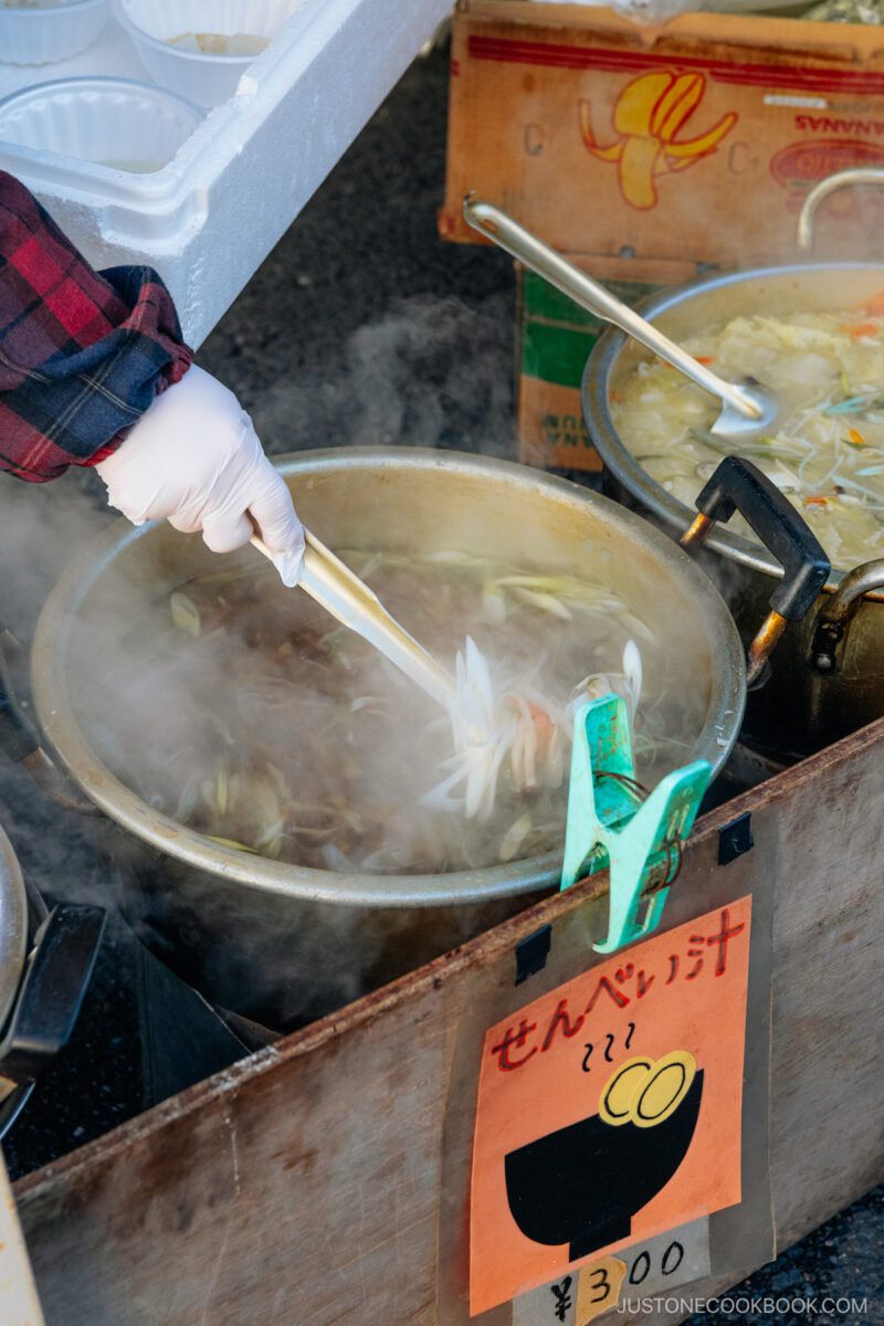 Person making soup with mushrooms, carrots, green onions and rice crackers