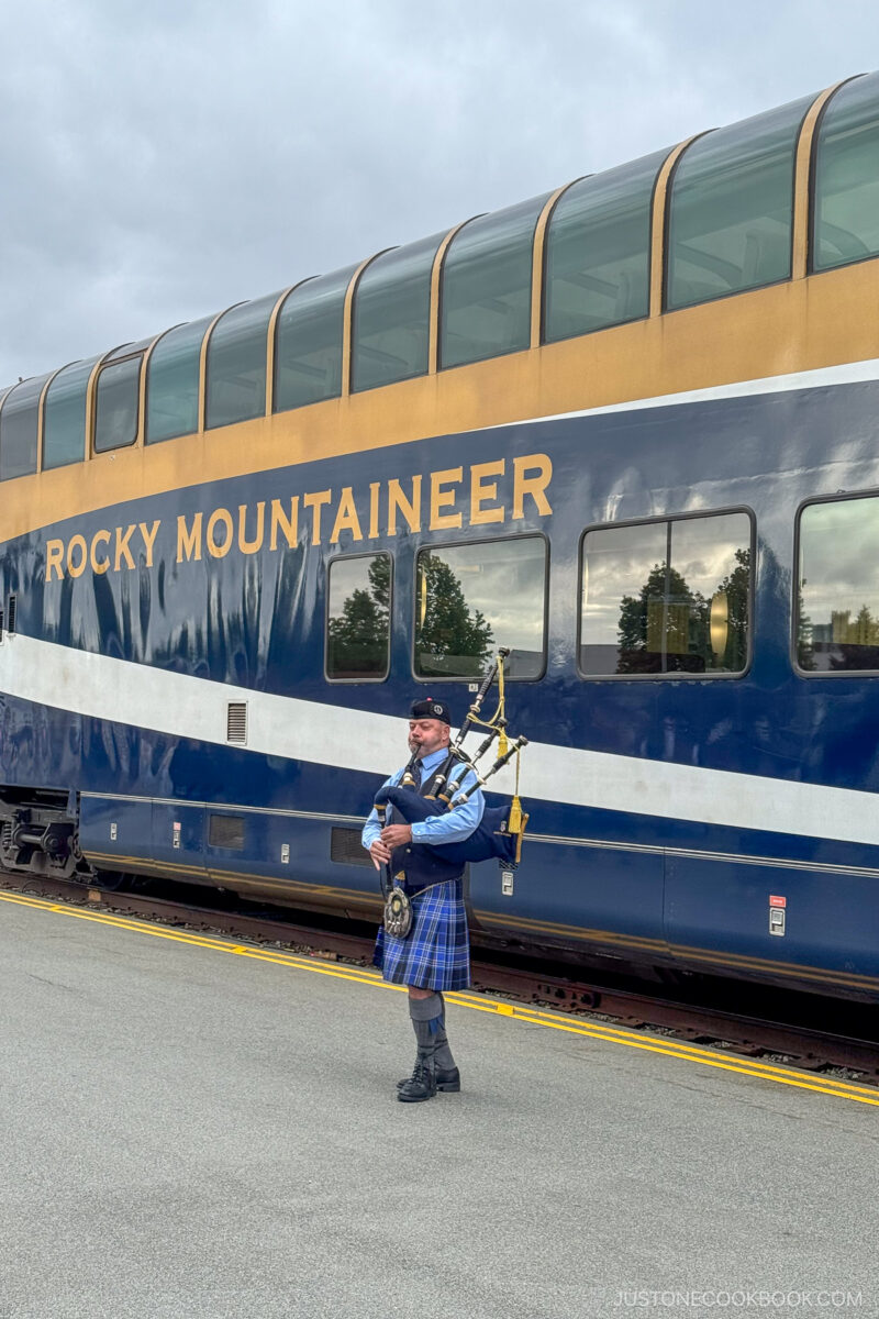 a person playing bagpipe in front of Rocky Mountaineer train