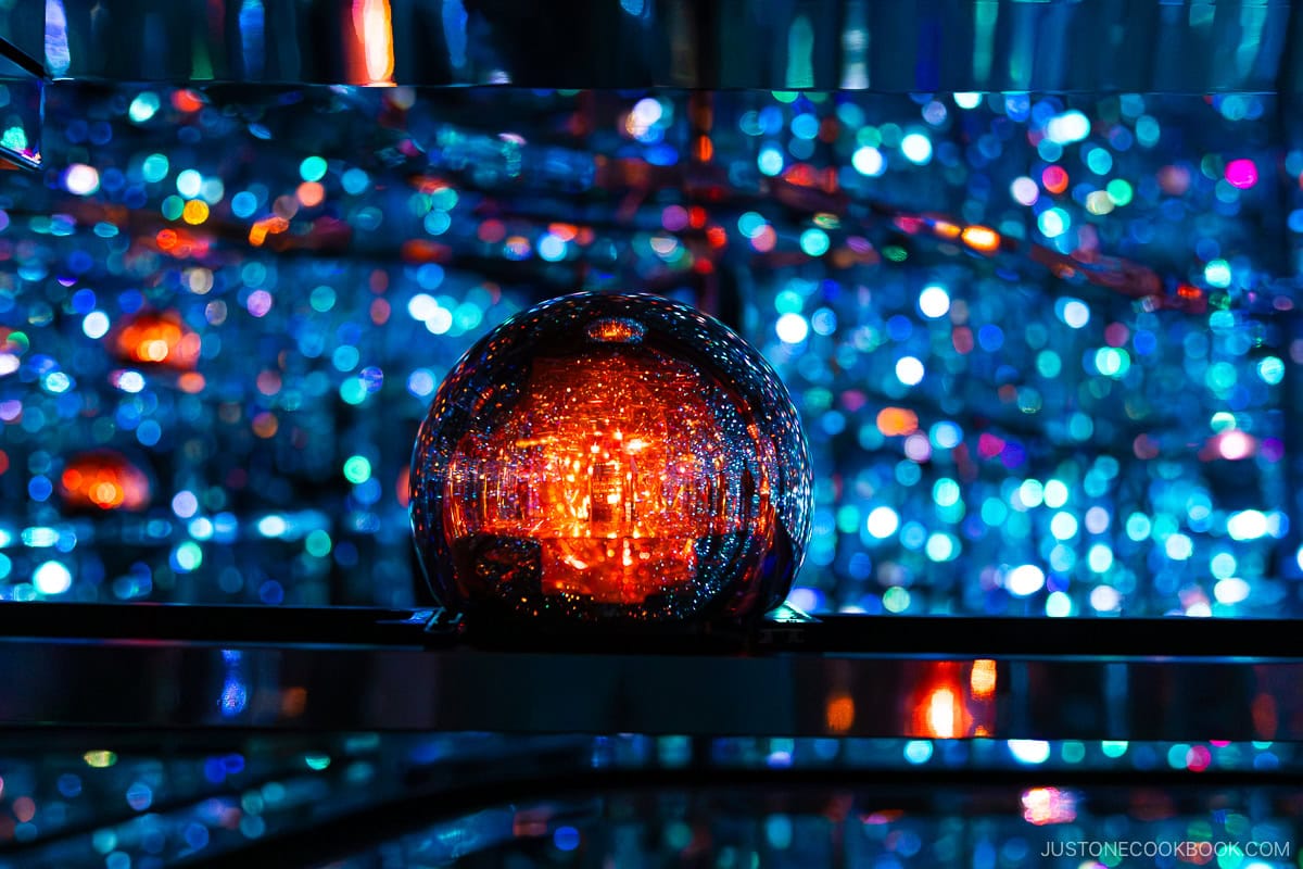 A mirrored ball reflecting red LED lights, rolling down a ramp