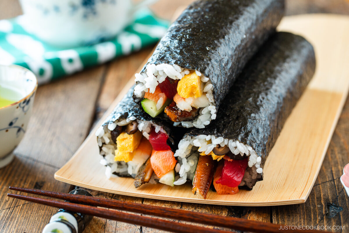 A rectangular plate containing three ehomaki, or uncut sushi rolls, prepared for setsubun festival.