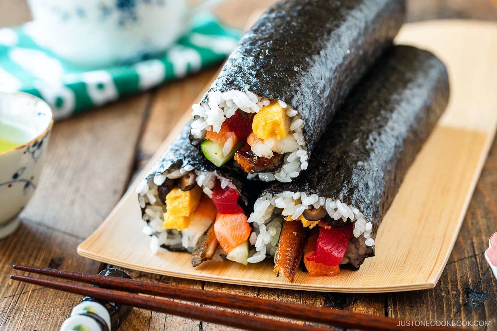 A rectangular plate containing three ehomaki, or uncut sushi rolls, prepared for setsubun festival.