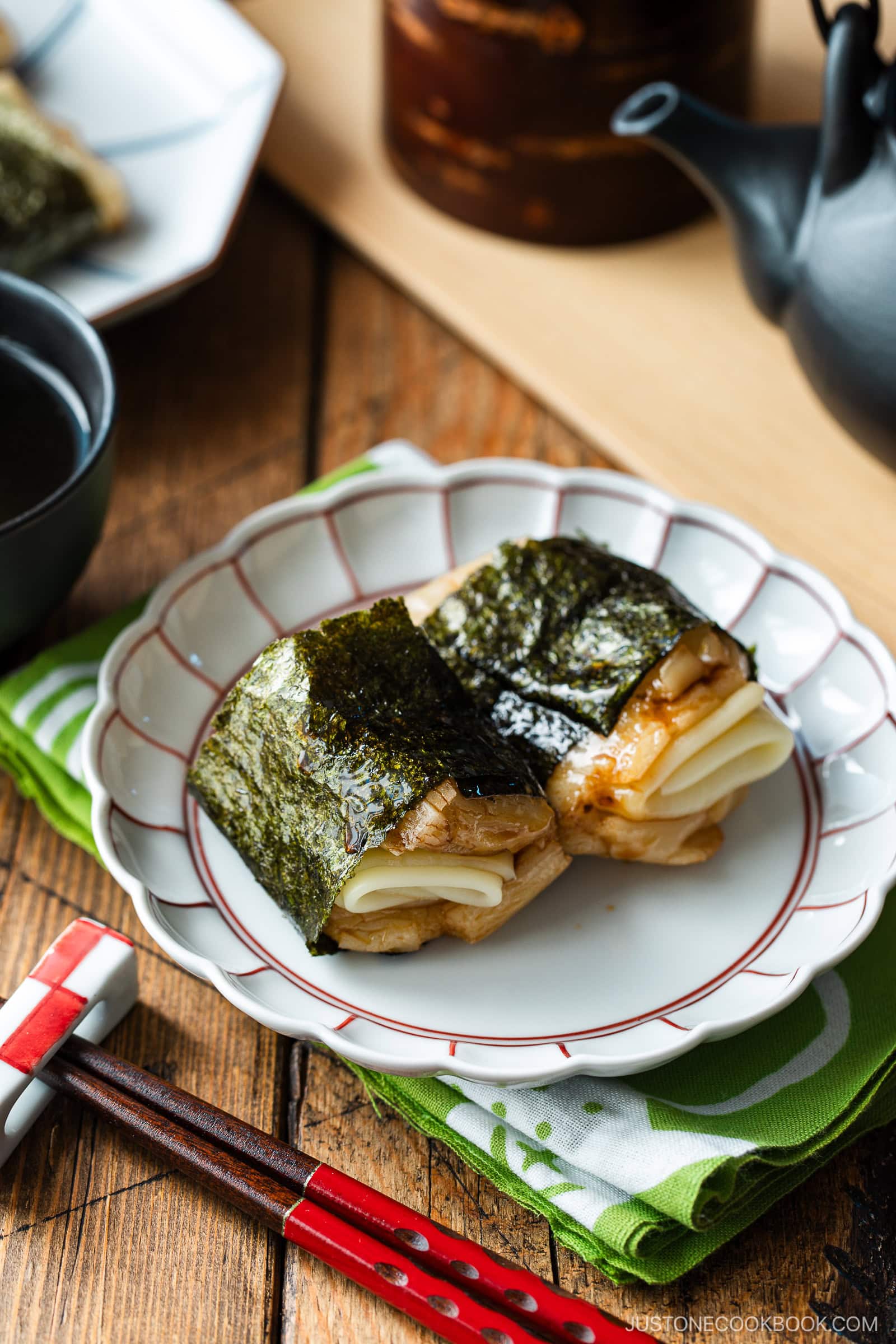 A round fluted plate containing cheese-stuffed Isobeyaki Mochi wrapped with nori seaweed.