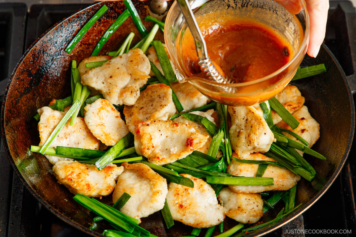 Drizzling the sauce over the chicken and garlic chives.