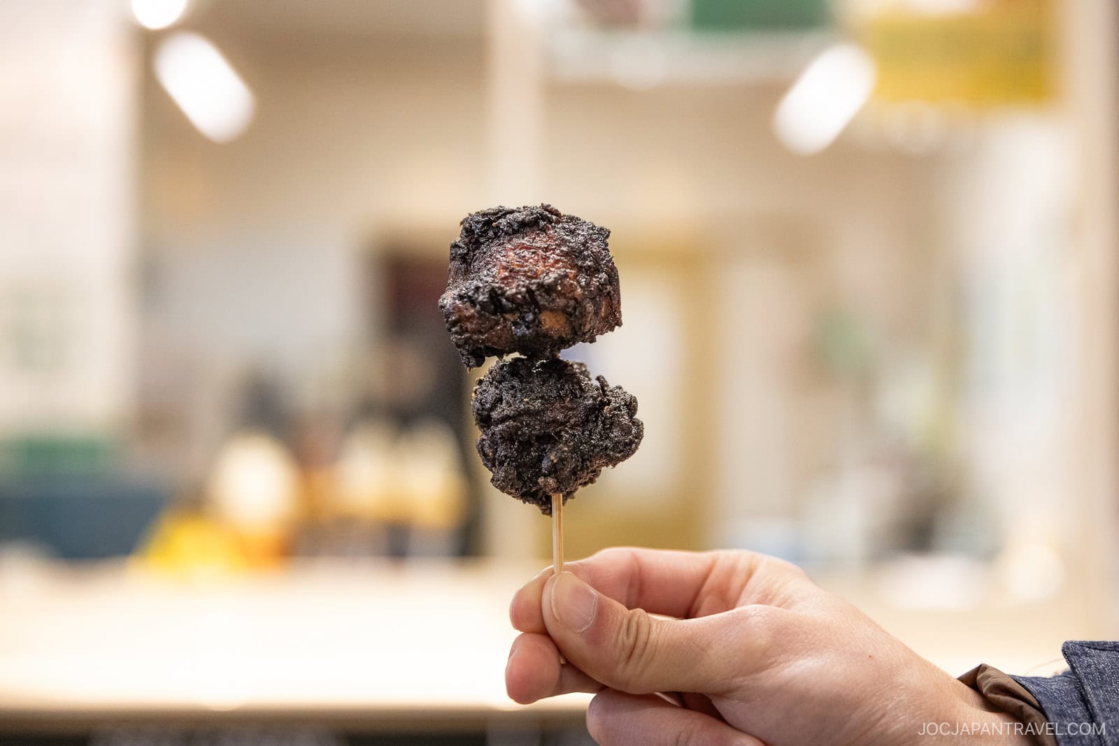Black coated fried chicken on a skewer