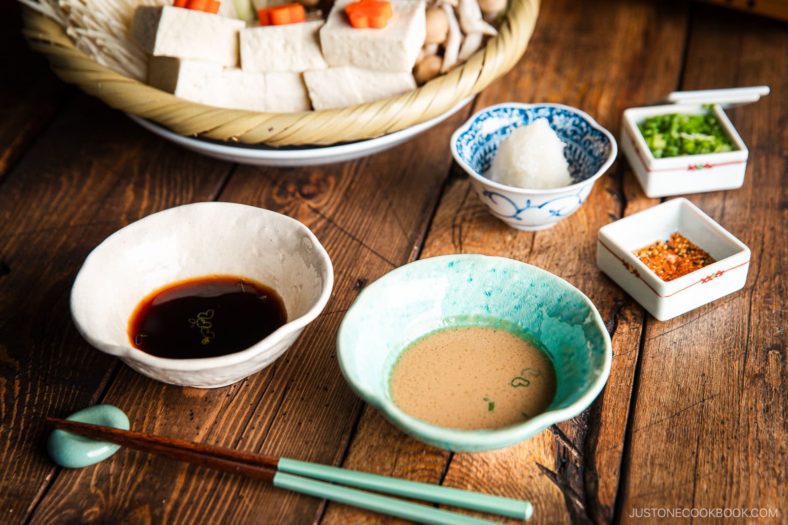 Dipping sauce bowls containing ponzu in one of them and the other in sesame sauce.