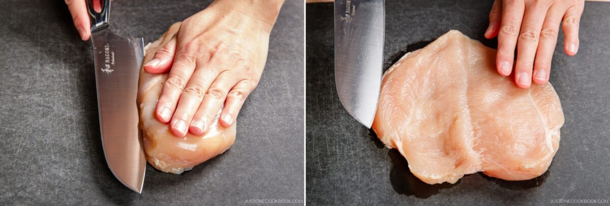 A person prepares chicken nanban by using a large knife to cut a raw chicken breast in half horizontally on a dark cutting board, holding the chicken steady with one hand.